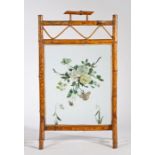 Early 20th Century bamboo fire screen, the handle above a wavy line and flower painted glass panel