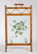 Early 20th Century bamboo fire screen, the handle above a wavy line and flower painted glass panel