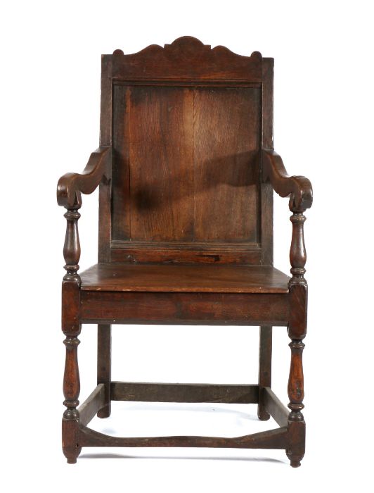 18th Century oak armchair, the arched top rail above a single panel back and solid seat flanked by