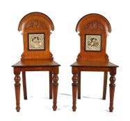Pair of Victorian oak hall chairs, the arched backs above a tile to each by John Moyr Smith from the