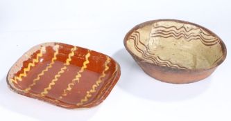 Two 19th Century slipware baking dishes, the first in a brick red glaze and yellow wriggles, 32cm