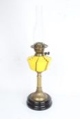 Oil lamp with clear glass chimney above a yellow and brown glass reservoir, reeded and acanthus leaf