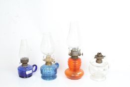 Three hand oil lamps, two with blue glass reservoirs, oil lamp with orange glass reservoir (4)