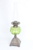 Oil lamp with clear glass chimney, green glass reservoir and scroll cast metal foot, 55cm high