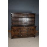 20th Century oak dresser and rack, with a wavy pediment and two shelves, the base with two cupboards