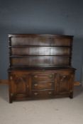 20th Century oak dresser and rack, with a wavy pediment and two shelves, the base with two cupboards