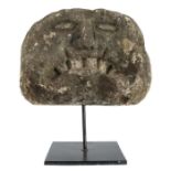 A carved stone head, possibly Anglo-Norman, circa 1150, with prominent down-turned grimacing mouth