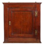 A George II joined oak wall cupboard, circa 1750, having a single-panelled cupboard door, framed by