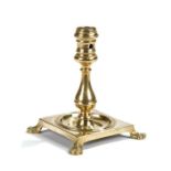 Early 18th Century candlestick, the socket above a baluster column and square base raised on four