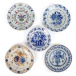 A group of five Delft plates, one designed with large flowers before  a fence, 19.5cm diameter;