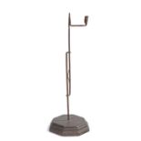 A floor standing ironrush light and candle holder, the jaws and candleholder above a sprung