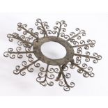 An 18th century iron trivet, the central circular frame with radiating multiple scroll arms, above