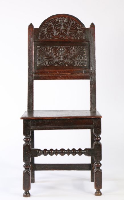 A Charles II oak backstool, Lancashire/Cheshire, circa 1680, the arched cresting foliate carved,