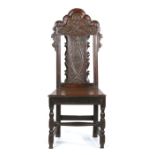 An early 18th Century oak side chair, circa 1700, the arched top rail above a flower and inlaid