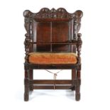 An unusual oak open armchair, dated 1718, Cumbria, the scroll arched top rail carved with