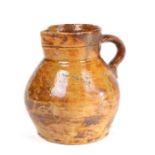 A George III honey glazed pottery jug, possibly West Country, with a spout and loop handle above the