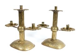 A pair of sheet-brass twin-branch candlesticks, circa 1905, each with a square section pillar, and