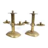 A pair of sheet-brass twin-branch candlesticks, circa 1905, each with a square section pillar, and