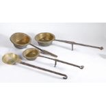 A collection of four early 18th Century brass and steel cooking pots, each with a brass pan and