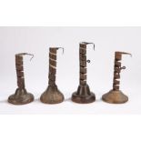 Four wrought iron and wooden candlesticks, French, circa 1800, each with a stem formed from a