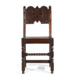 A Charles II oak backstool, Manchester, circa 1670, the arched solid back board strap-work carved,