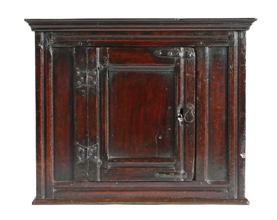 Charles II oak hanging cupboard, circa 1660, the concave cornice above a central panel door