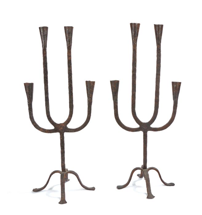 A pair of wrought iron candelabra, each with four arms with conical socket, on a tripod base, 53cm