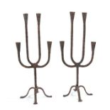 A pair of wrought iron candelabra, each with four arms with conical socket, on a tripod base, 53cm