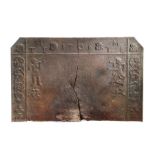 A early 18th century cast iron fire back, of rectangular form with canted corners, headed by the