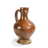 A 17th century stoneware jug, with a brown speckled body above ring decorations and foot,
