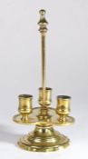 An unusual brass candlestick, with carrying handle and trefoil drip tray with three candle sockets,