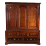 A George III oak press cupboard, circa 1800, the pediment above a central arched fielded panel,