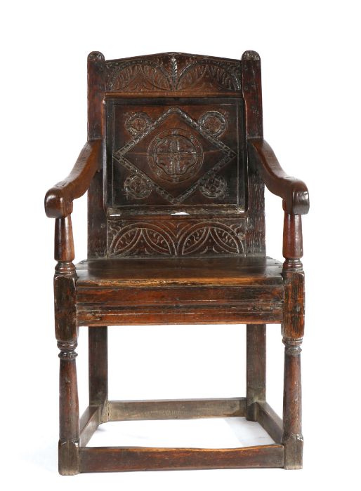 A Charles I oak panel-back open armchair, West Country, circa 1630, the pediment top rail lunette-