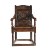 A Charles I oak panel-back open armchair, West Country, circa 1630, the pediment top rail lunette-