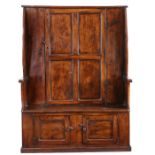 A George III elm 'bacon' settle, West Country, circa 1780, the back with a quadruple-panelled door