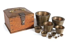 A set of 19th century bronze cup weights, the graduated set of twelve in their original oak and
