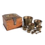 A set of 19th century bronze cup weights, the graduated set of twelve in their original oak and