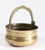 A 17th Century brass stoup, with a swing dolphin handle above the ring turned body, 16cm diameter