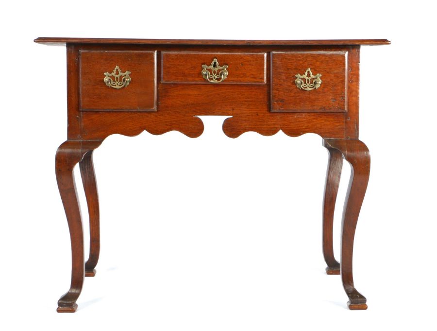 A George III oak lowboy, the rectangular top above three drawers and shaped apron, on cabriole