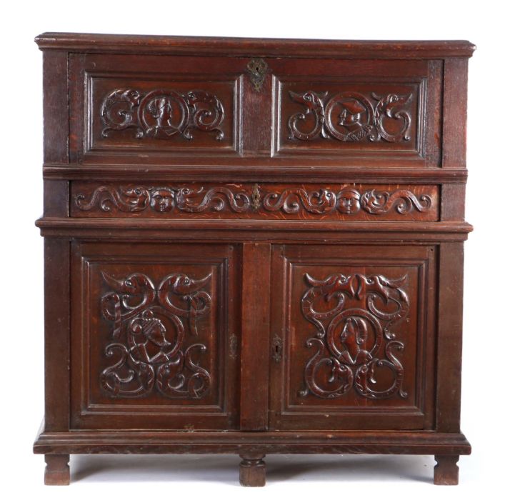 An early 16th century oak cupboard, French, the rectangular top above a hinged fall carved with
