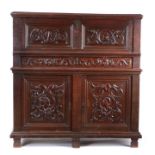 An early 16th century oak cupboard, French, the rectangular top above a hinged fall carved with