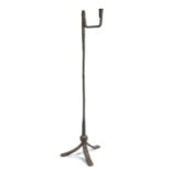 A wrought iron floor standing rushlight and candle holder, the nips and folded candle socket above