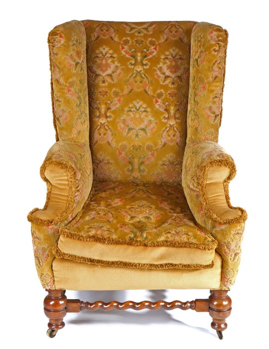 A Victorian walnut and upholstered wing armchair, the high padded back above a squab-cushion and