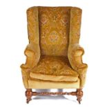 A Victorian walnut and upholstered wing armchair, the high padded back above a squab-cushion and