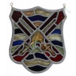 A stained glass panel, of shield shape, designed with crossed swords, 24cm wide, 28cm high