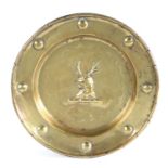 A small brass alms dish Centred by a stag crest, the rim with eight circular boss and rolled rim