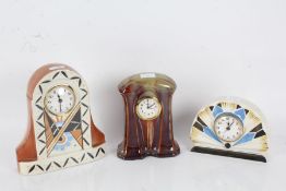Three Art Deco pottery mantle clocks, two decorated with bright colours, the other with green and