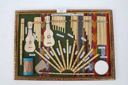 Gilt framed board depicting instruments native to Bolivia, the frame 37.5cm wide x 26.5cm high