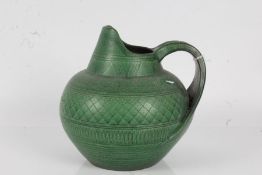 Wilhelm Kagel, sgraffito green glazed jug, of bulbous form, paper label to base, 22cm high