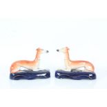 Pair of Staffordshire Greyhounds in a reclined position on blue bases, 17cm long